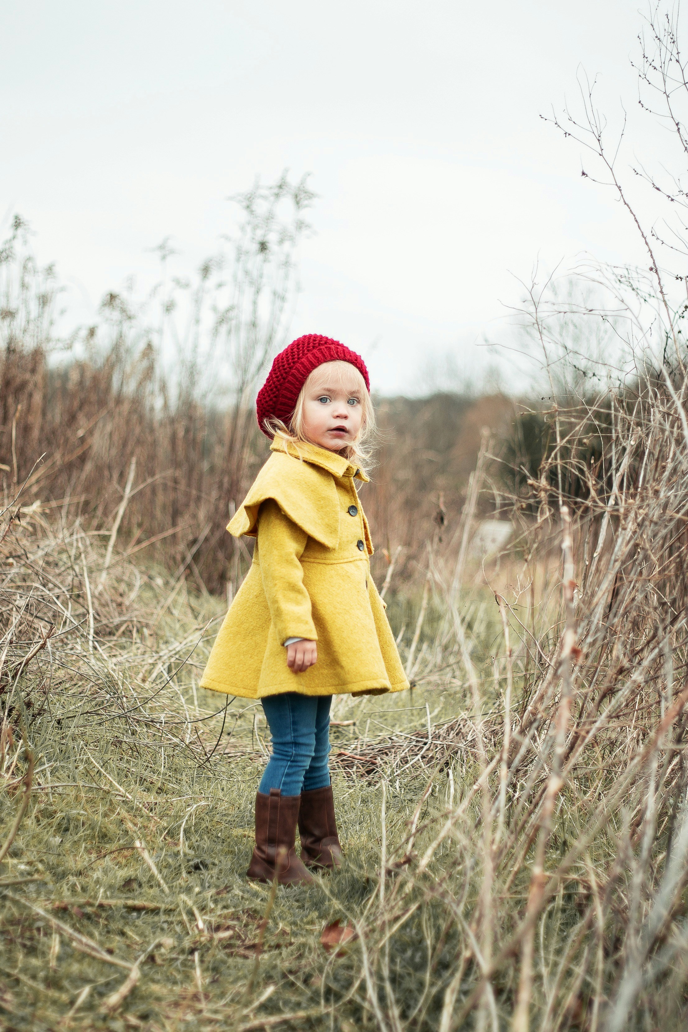 Original photo of a young girl in a yellow coat standing outdoors